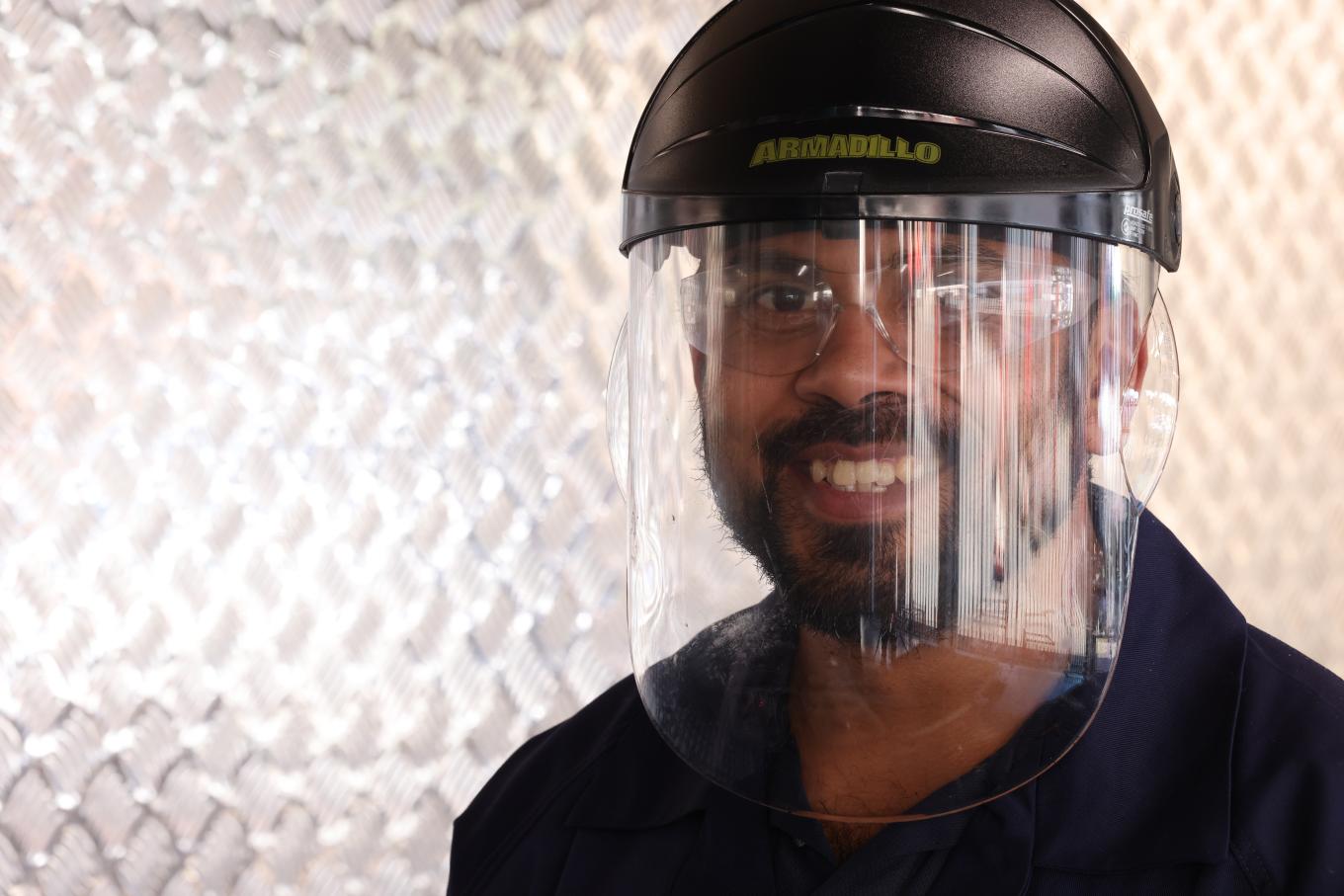 Laboratory technician wearing protective helmet, goggles and face shield, demonstrating Colas Australia’s commitment to safety, research and innovation in advanced pavement materials.